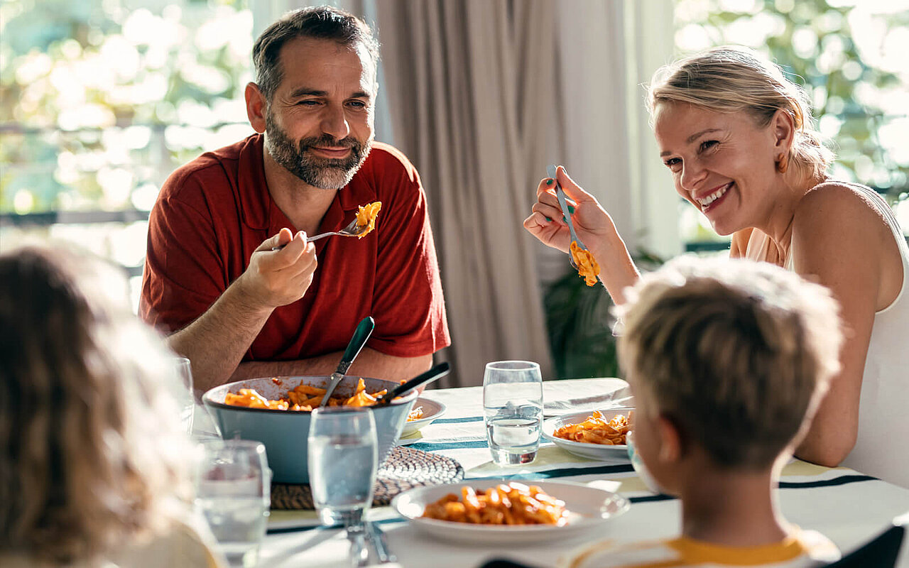 Eine Familie am Küchentisch isst Spaghetti 
